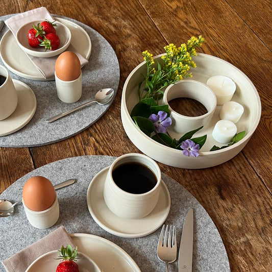beigefarbener handgedrehter Dekokranz aus Steinzeugton auf einem gedeckten Frühstückstisch
