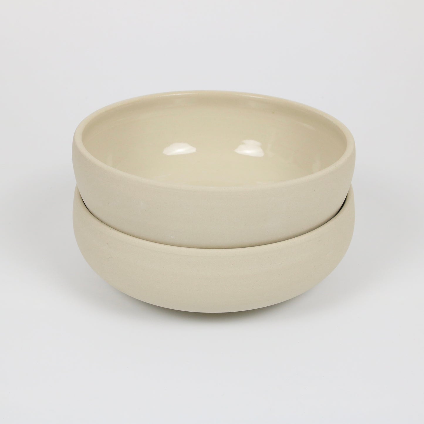 zwei große flache beigefarbene handgedrehte Bowls aus Steinzeugton, gestapelt
