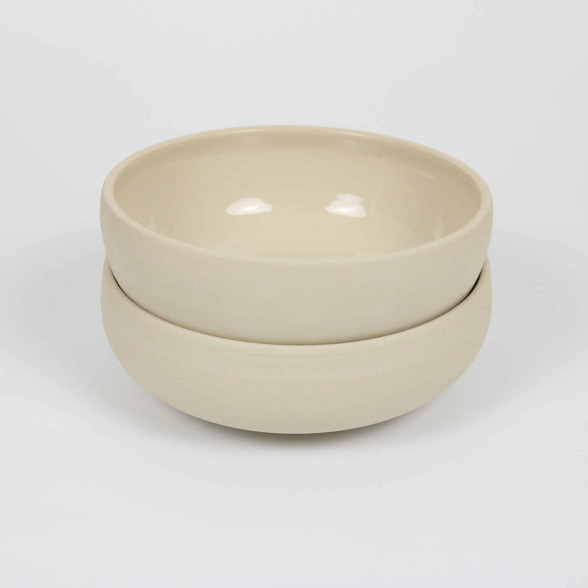 zwei große flache beigefarbene handgedrehte Bowls aus Steinzeugton, gestapelt