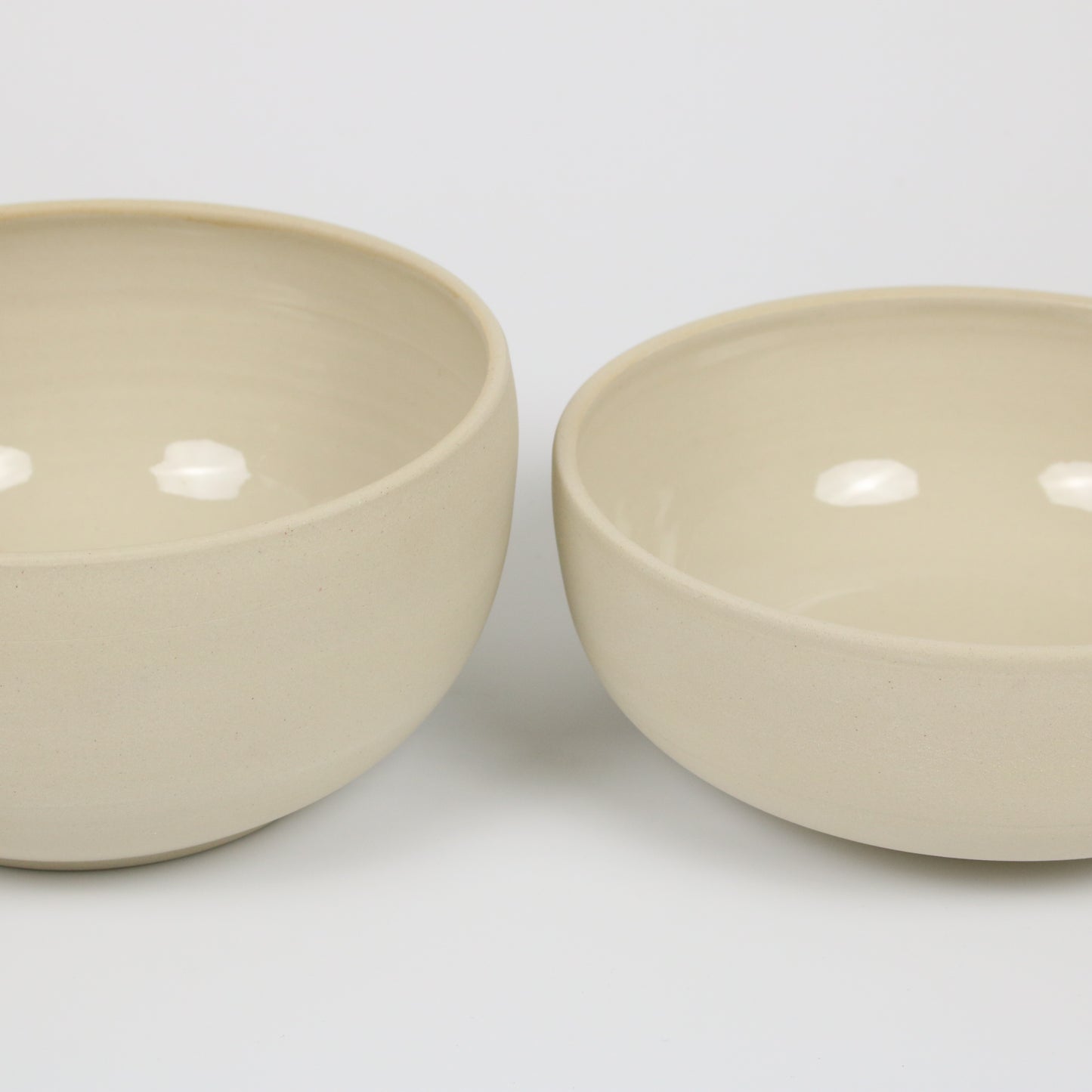 zwei große beigefarbene handgedrehte Bowls aus Steinzeugton, unterschiedlich hoch