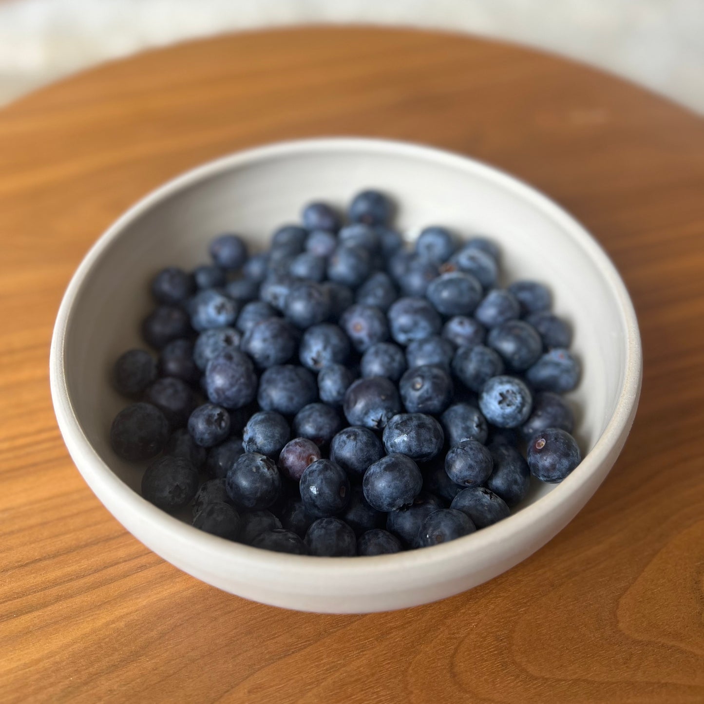 große flache beigefarbene handgedrehte Bowl aus Steinzeugton mit Blaubeeren gefüllt